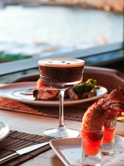 Espresso martini beside a lobster dish